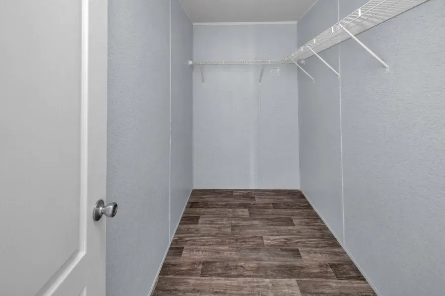 A walk in closet with wooden floors and white walls.