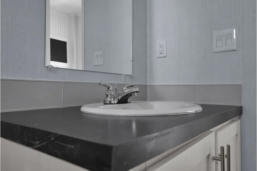 A bathroom with a sink , mirror , and cabinets.