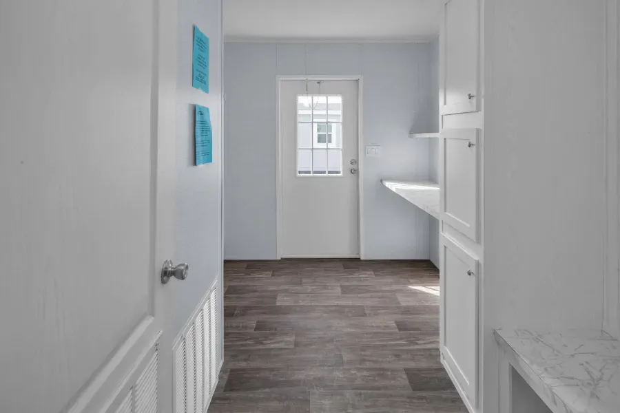 A hallway in a house with a white door and a wooden floor.