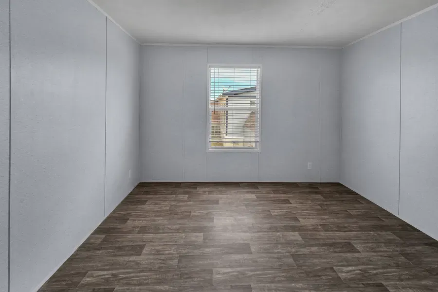 An empty room with a window and a wooden floor.