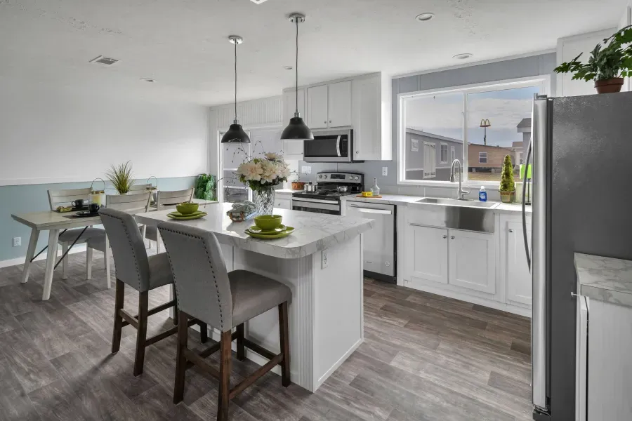 A kitchen with white cabinets , a large island , a dining table and chairs.