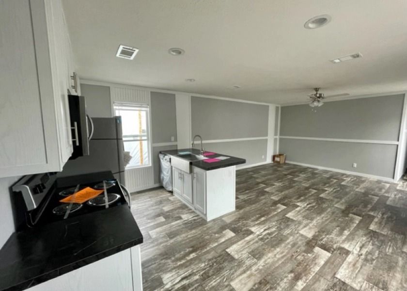 A kitchen with a stove , refrigerator , sink and a ceiling fan.