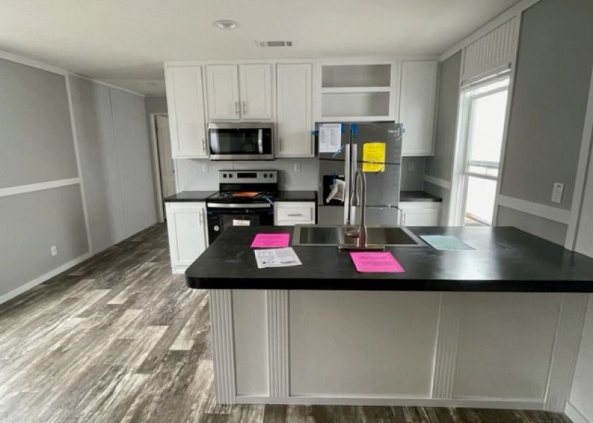 A kitchen with a refrigerator , sink , stove and microwave.