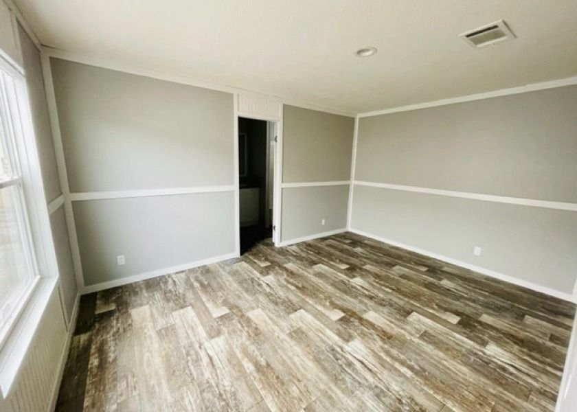An empty room with a wooden floor and gray walls.