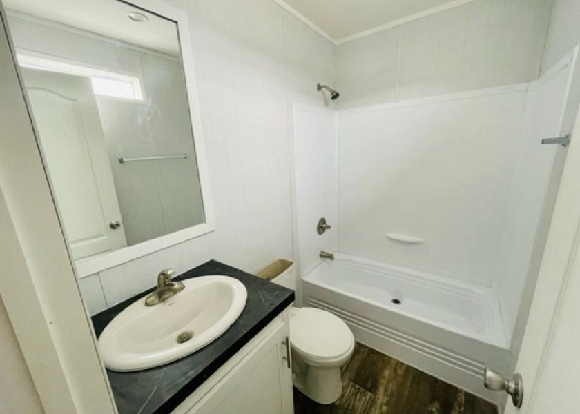 A bathroom with a sink , toilet , bathtub and mirror.