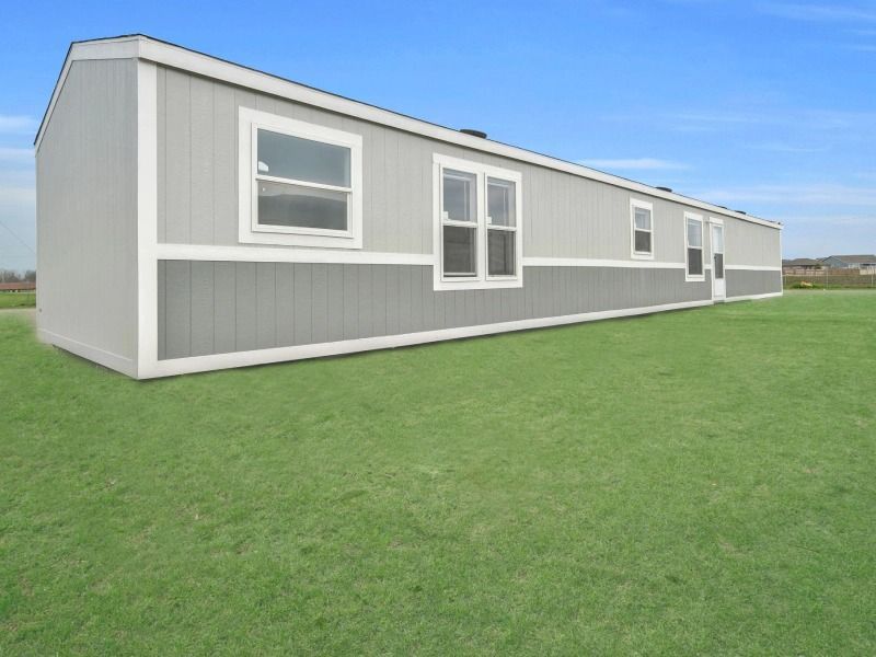 A mobile home is sitting on top of a lush green field.