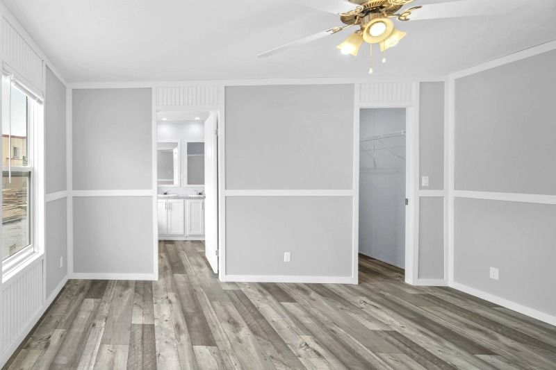 An empty living room with hardwood floors and a ceiling fan.