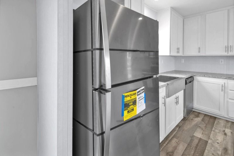 A stainless steel refrigerator in a kitchen with white cabinets.