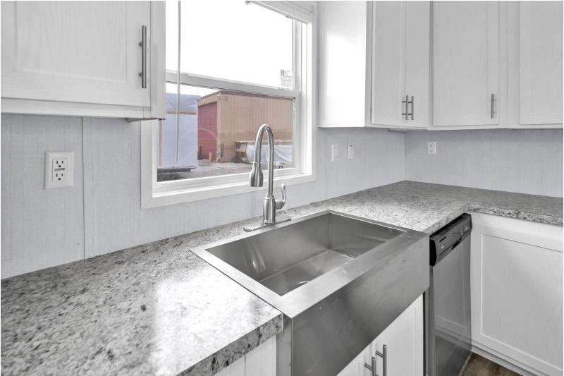A kitchen with a stainless steel sink and granite counter tops.