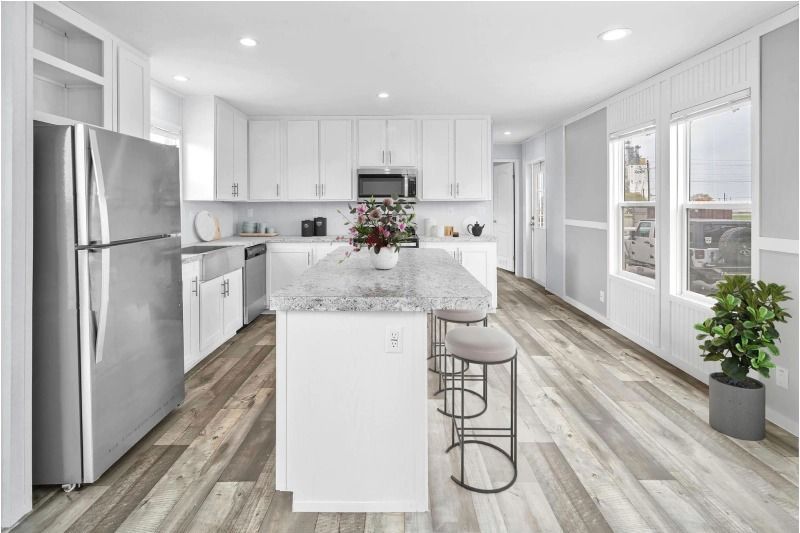 A kitchen with white cabinets , stainless steel appliances , and a large island.