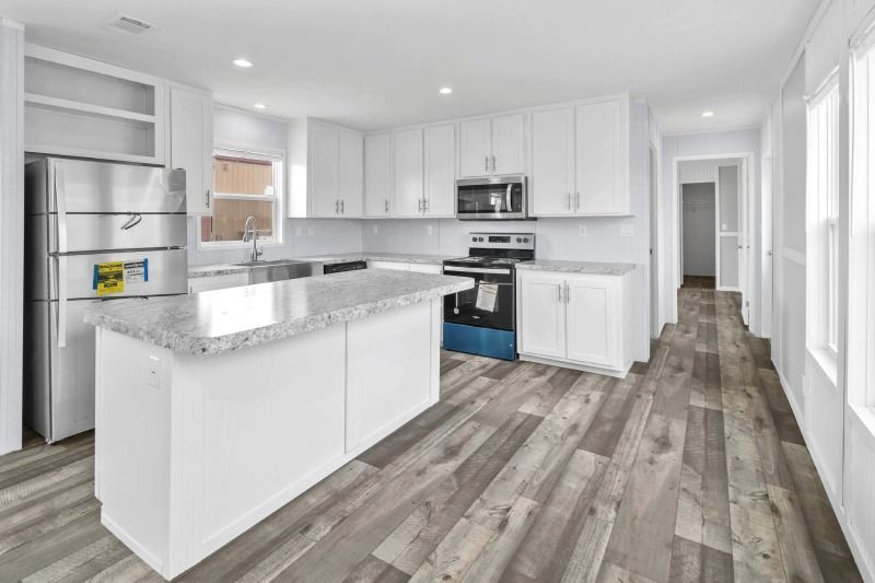 A kitchen with white cabinets , granite counter tops , stainless steel appliances and hardwood floors.
