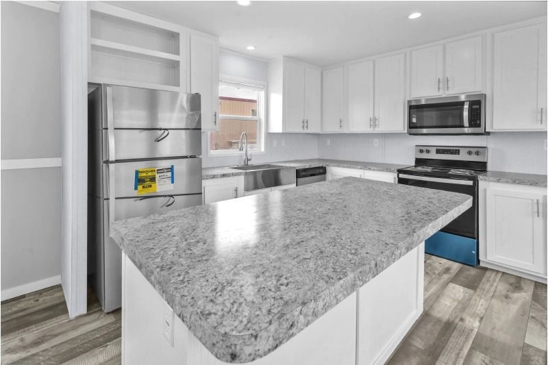 A kitchen with white cabinets , granite counter tops , stainless steel appliances and a refrigerator.
