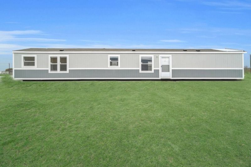 A mobile home is sitting on top of a lush green field.