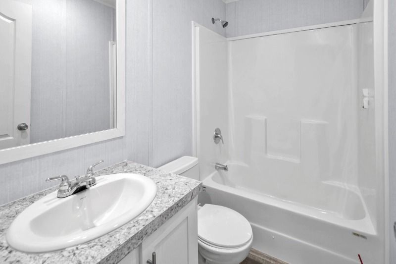 A bathroom with a sink , toilet , tub and mirror.