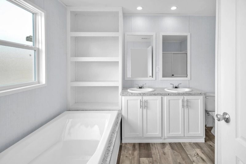 A bathroom with two sinks , a tub , and a window.