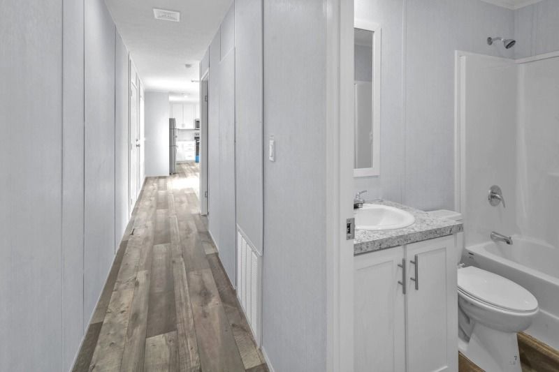 A bathroom with a sink , toilet and bathtub in a hallway.