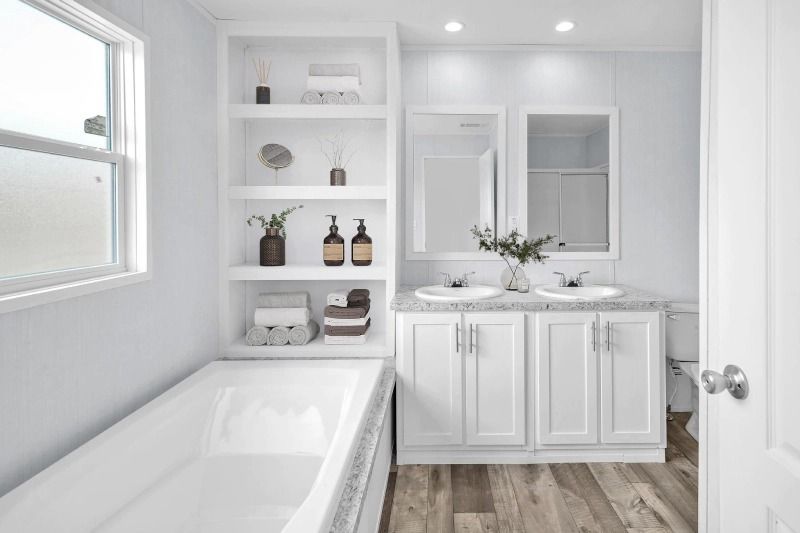 A bathroom with two sinks , a tub , and a window.