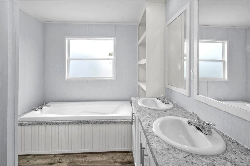 A bathroom with two sinks , a tub and a window.