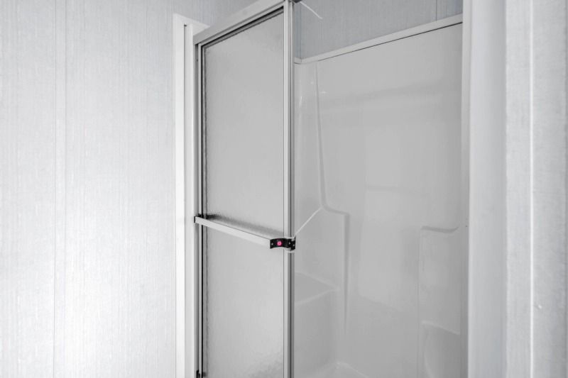 A shower stall with a clear glass door in a bathroom.