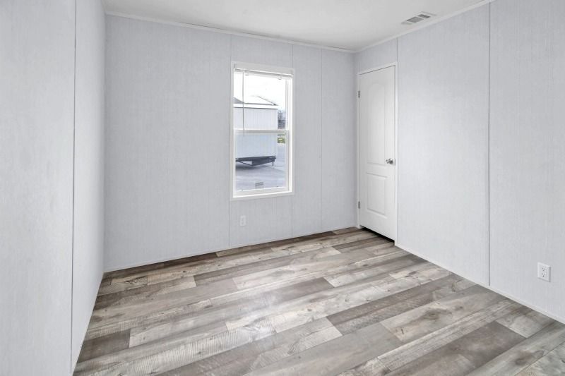 An empty room with a wooden floor and a window.