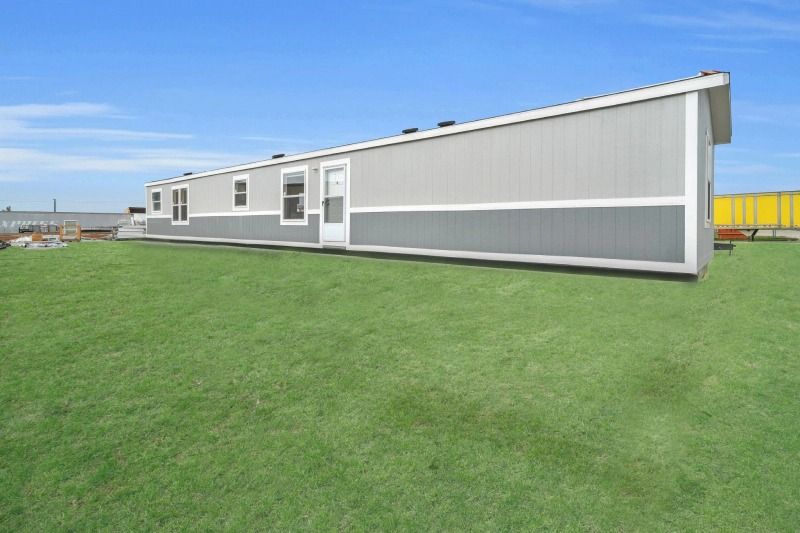 A mobile home is sitting on top of a lush green field.