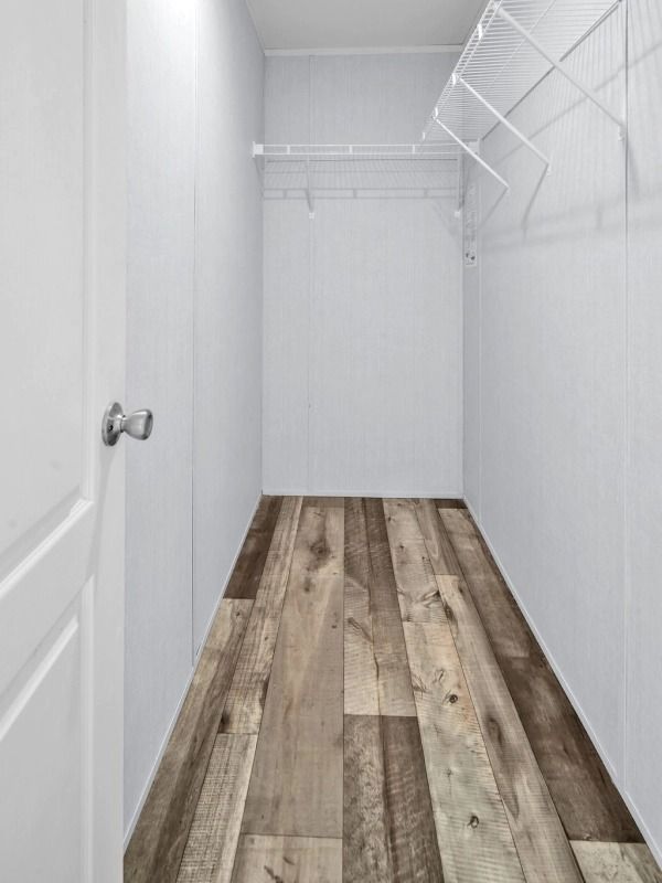 A walk in closet with wooden floors and white walls.