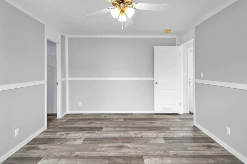 An empty room with a ceiling fan and a wooden floor.