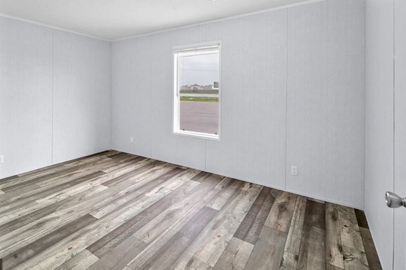 An empty room with hardwood floors and a window.