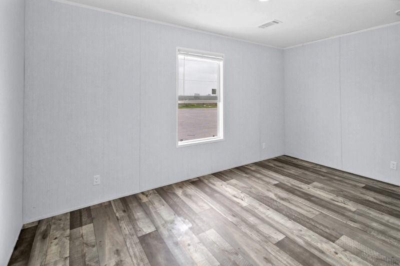 An empty room with hardwood floors and a window.