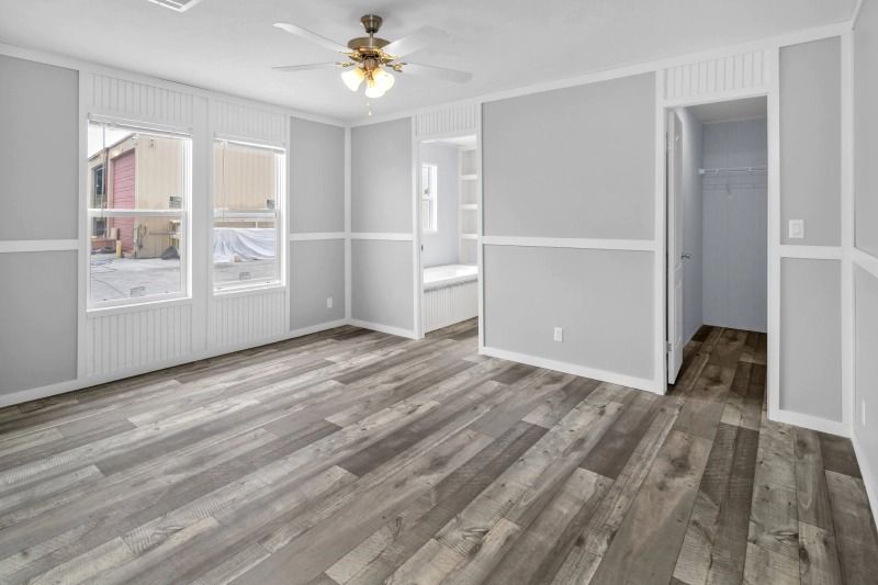 A large empty room with hardwood floors and a ceiling fan.