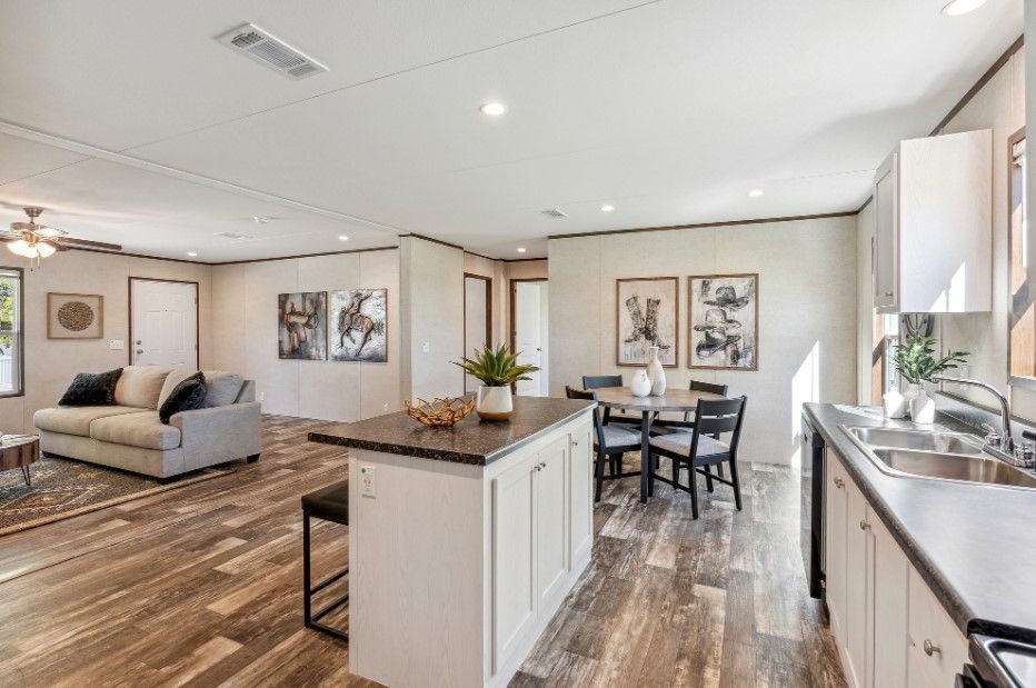 A living room with a couch , table and chairs and a kitchen with a sink.