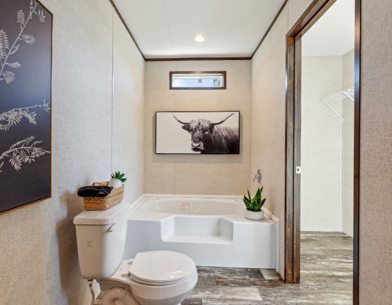 A bathroom with a toilet , tub and a picture of a bull on the wall.