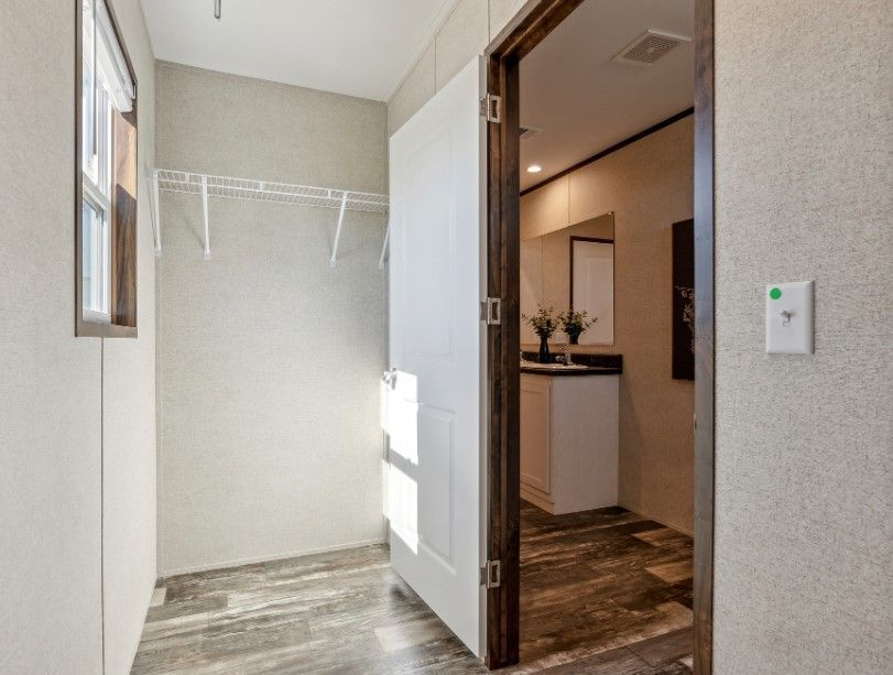 A walk in closet in a mobile home with a bathroom and sink.