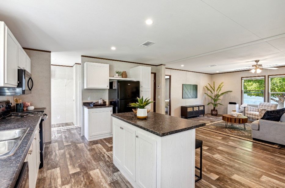A kitchen and living room in a mobile home with a large island in the middle.