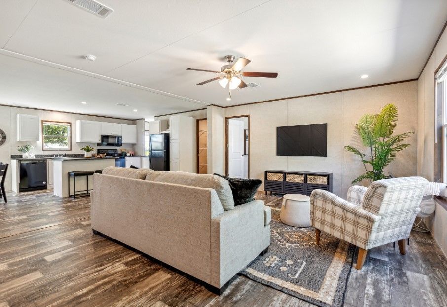 A living room with a couch , chairs , and a flat screen tv.