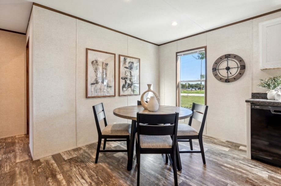 A dining room with a table and chairs and a clock on the wall.