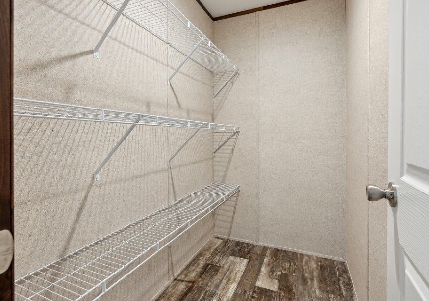A walk in closet with lots of shelves and a door.