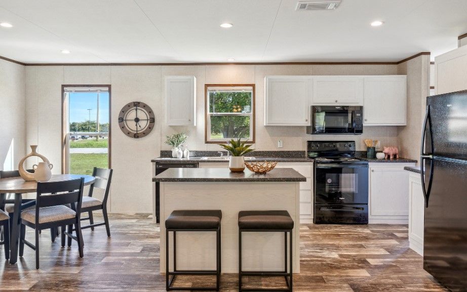 A kitchen and dining room in a mobile home with stainless steel appliances.