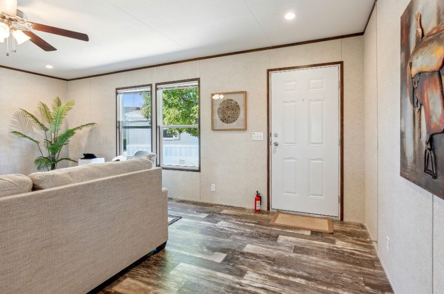A living room with a couch , ceiling fan , and a door.