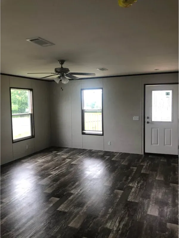 An empty living room with hardwood floors and a ceiling fan.