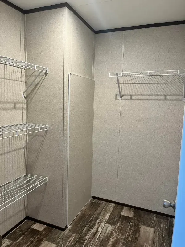 A walk in closet with lots of shelves and a blue door.