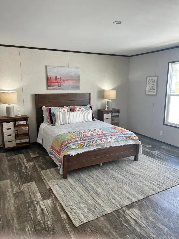 A bedroom with a bed , nightstands , lamps and a rug.