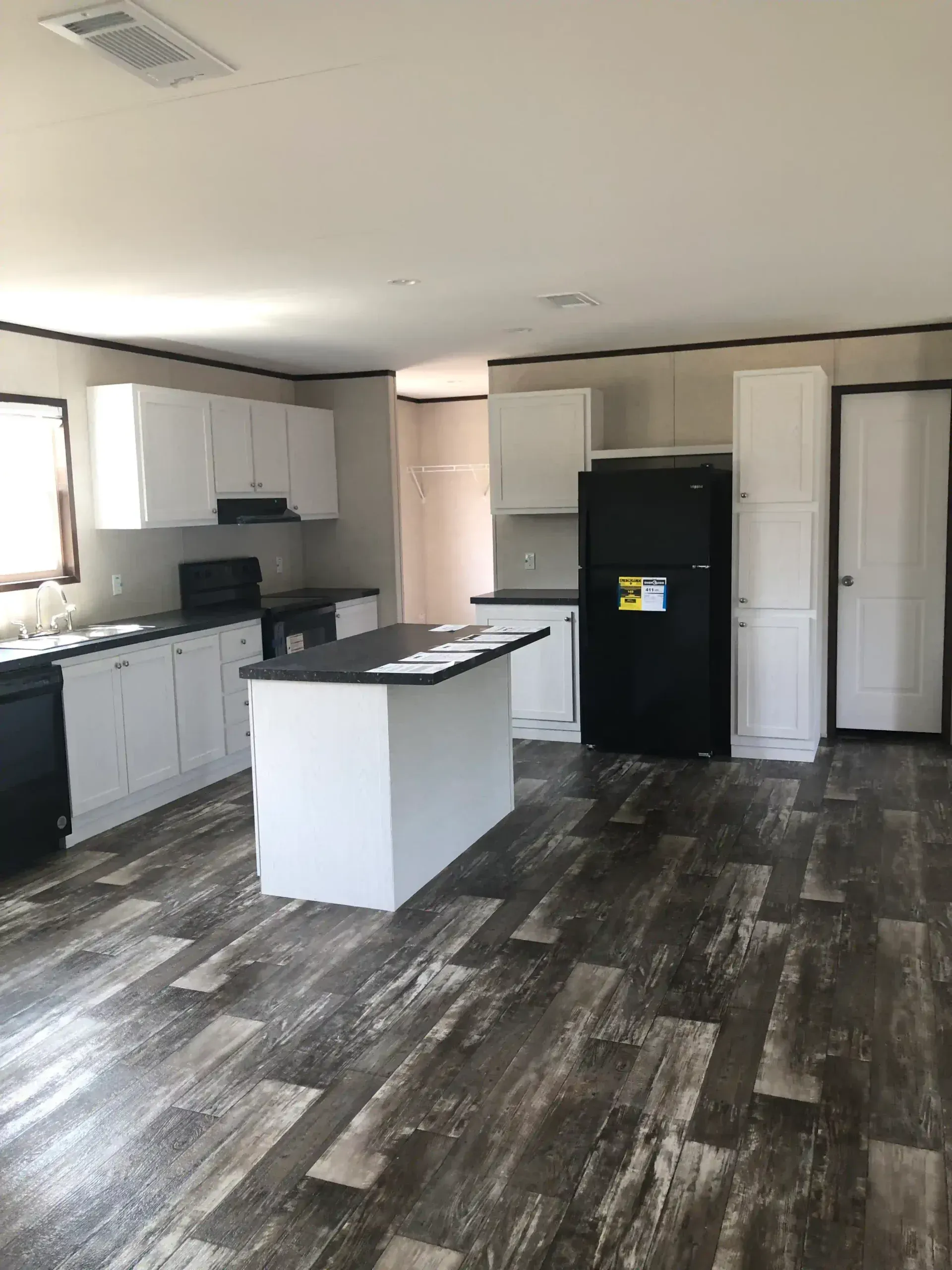 A kitchen with a large island and a black refrigerator