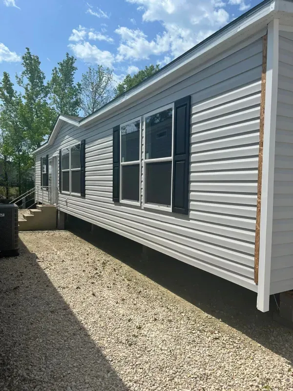 A white mobile home with black shutters and stairs