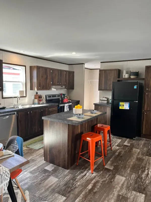 A kitchen with a large island and a black refrigerator.
