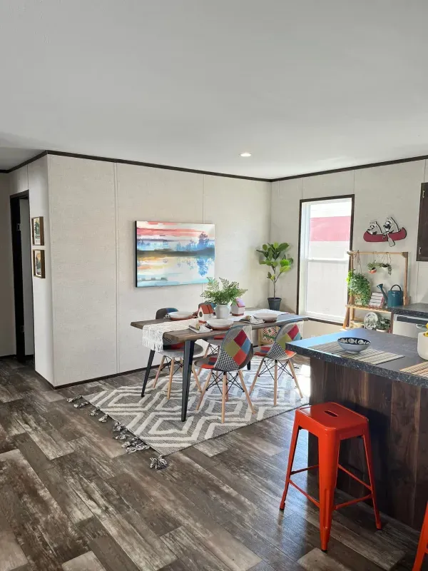 A dining room in a mobile home with a table and chairs.