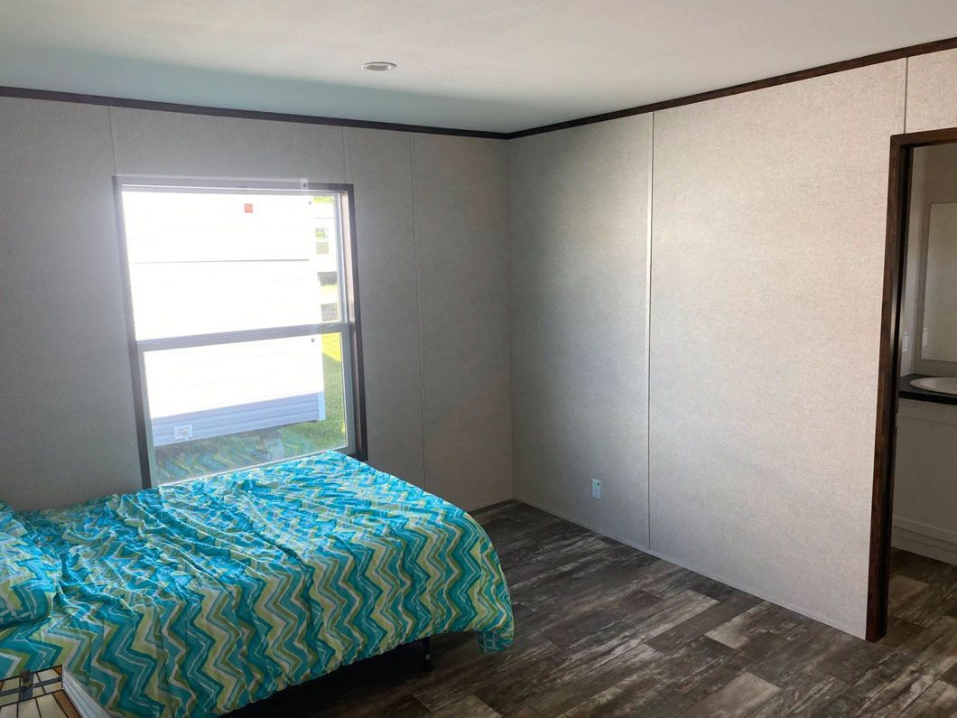 A bedroom with a bed and a window in a mobile home.