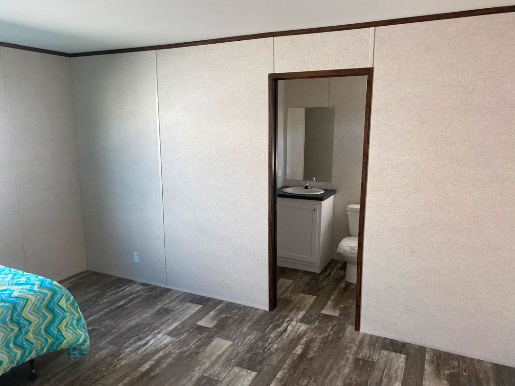 A bedroom with a bed , toilet , sink and mirror.