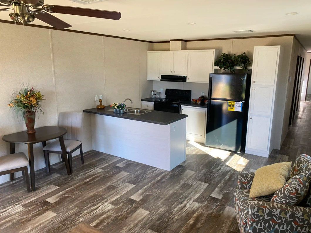 A living room with a table and chairs and a kitchen with a refrigerator.
