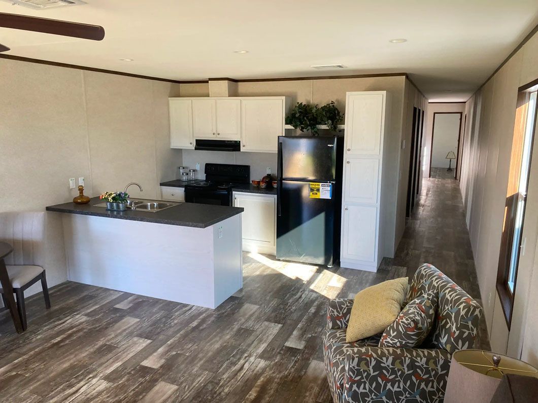 A living room filled with furniture and a kitchen with a refrigerator.